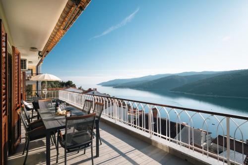 a balcony with tables and chairs and a view of a lake at Blue Horizon Apartment a Seaside Escape in Rabac in Rabac
