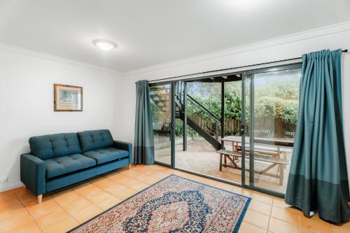 a living room with a blue couch and a sliding glass door at Blue Haven Ocean Views & Pool in Gnarabup