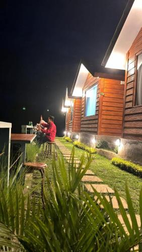 a person sitting in a chair outside a house at night at Pondok Alengkong in Bangli