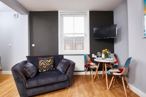 a living room with a couch and a table at Delven House- Serviced Apartments in Castle Donington