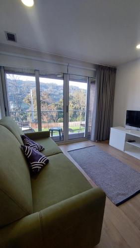 a living room with a green couch and a large window at Welcome Douro - Eco Camping Resort in Cinfães