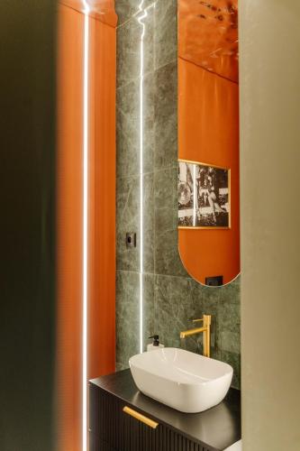 a bathroom with a white sink and an orange wall at Le Falcoz in Saint-Jean-de-Maurienne