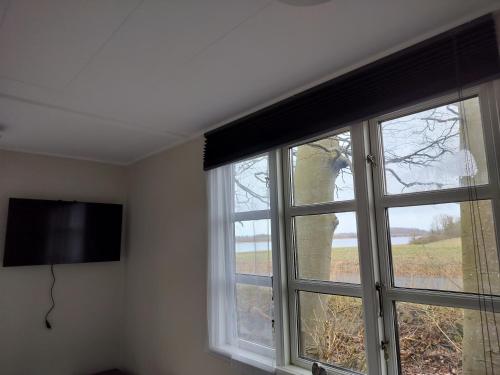 a room with two windows and a flat screen tv at Hytte med udsigt til Stege Nor in Stege
