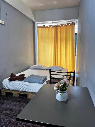 a room with two beds and a table with flowers on it at The New Normal House in Chiang Mai
