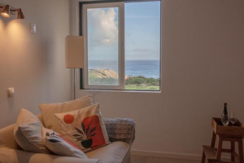 a living room with a couch and a large window at Seaview Ensuite rooms in Sagres centre - Casa Maluka in Sagres