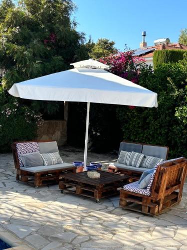 a white umbrella and two chairs and a table with an umbrella at LE CAROUBIER splendid 3 bedrooms bungalow in Zanaja