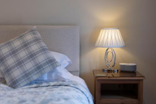 a bed with a table with a lamp on it at Canaston Oaks in Narberth