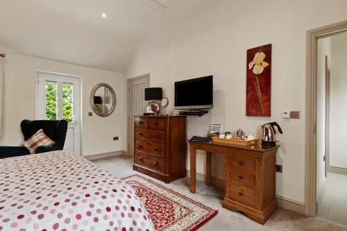 a bedroom with a bed and a dresser and a television at Canaston Oaks in Narberth