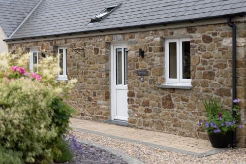a stone house with a white door and windows at Canaston Oaks in Narberth