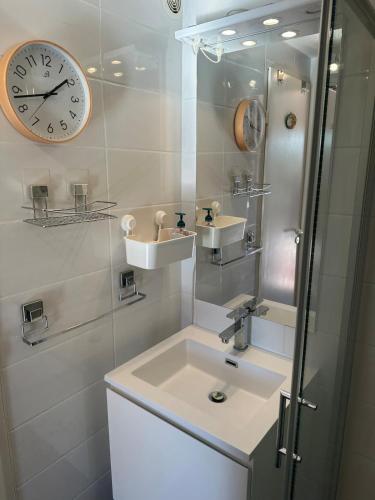 La salle de bains est pourvue d'un lavabo et d'une horloge murale. dans l'établissement Compact vacation house in Vidauban, à Vidauban