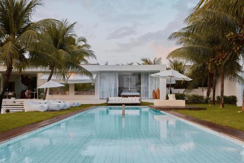 a swimming pool in front of a villa at Pe na Areia Boutique Hotel in Japaratinga