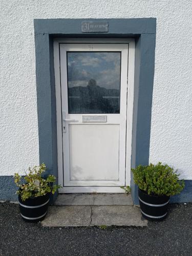 a white door with two potted plants in front of it at Seaview in Stornoway
