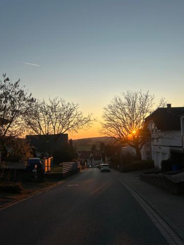 a car driving down a street with the sunset in the background at Ferienwohnung Schieferglück in Gründau