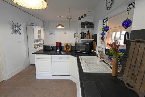 une cuisine avec des armoires blanches et un comptoir noir dans l'établissement WHITE BLUE House, à Biscarrosse