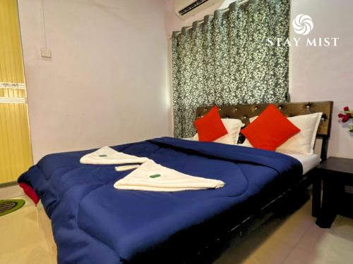 a bedroom with a bed with blue sheets and red pillows at StayMist - Marina Tide Villa in Alibaug
