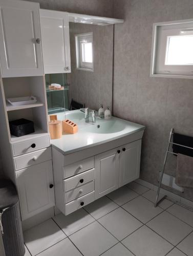 une salle de bain blanche avec un lavabo et un miroir dans l'établissement Maison proche Etretat, Le Havre, à Montivilliers