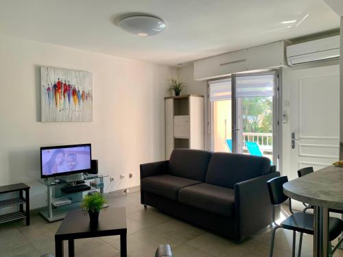 ein Wohnzimmer mit Sofa und Fernseher in der Unterkunft Beau Studio climatisé, parking privé Sanary centre in Sanary-sur-Mer