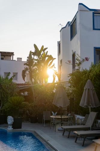 a pool with chairs and umbrellas next to a building at Artunc Hotel Bodrum in Bodrum City