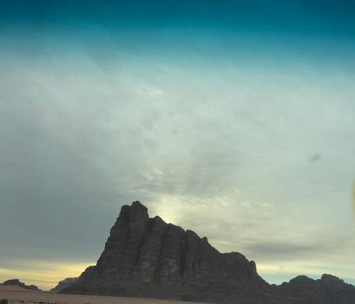 a mountain in the desert under a cloudy sky at Nara Wadi RUM Camp in Wadi Rum