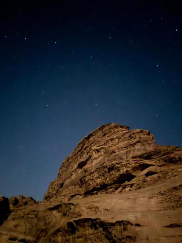 a mountain under a night sky with stars at Nara Wadi RUM Camp in Wadi Rum