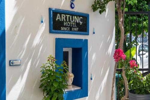 a sign for an arriving hotel on a wall with plants at Artunc Hotel Bodrum in Bodrum City