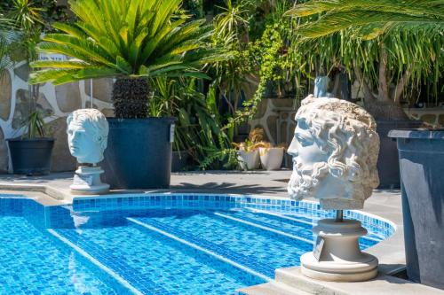 a swimming pool with statues of heads next to it at Artunc Hotel Bodrum in Bodrum City