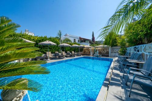 a swimming pool with chairs and umbrellas at Artunc Hotel Bodrum in Bodrum City