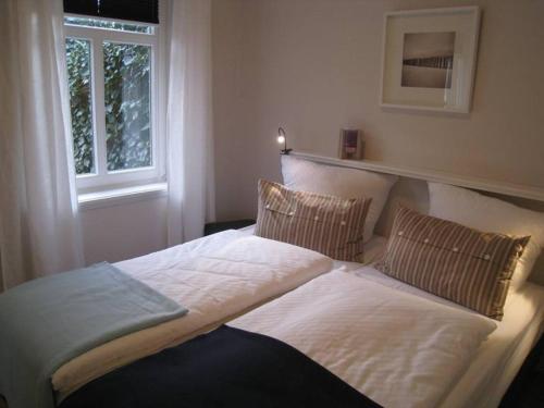 a large bed in a bedroom with a window at Sommergarten in Wyk auf Föhr