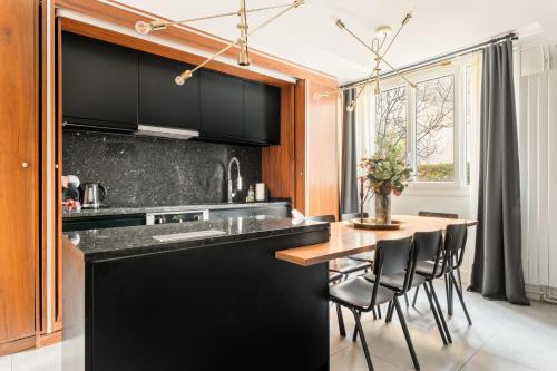 une cuisine avec des armoires noires et une table avec des chaises dans l'établissement Eiffel Tower - 4 Bedrooms like a Hotel, à Paris