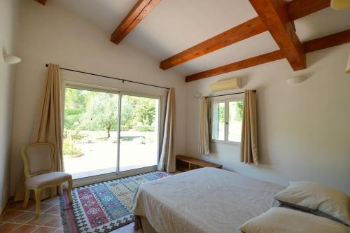 a bedroom with a bed and a large window at Piscine et tennis privés à proximité Aix en Provence in Rousset