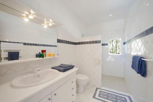 a white bathroom with a sink and a toilet at Piscine et tennis privés à proximité Aix en Provence in Rousset