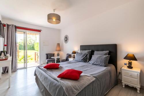 a bedroom with a large bed with red pillows on it at Gîte & Chambres d'Hôtes - Le Petit Bali in Saint-Pandelon