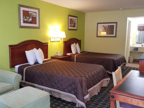 a hotel room with two beds and a couch at American Inn Columbia in Columbia