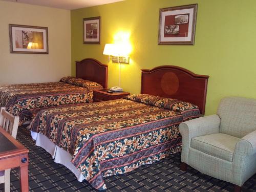 a hotel room with two beds and a chair at American Inn Columbia in Columbia