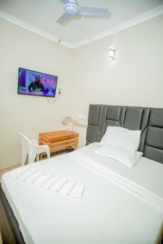 une chambre avec un lit et une télévision au mur dans l'établissement WayPoint Lodge, à Dar es Salaam