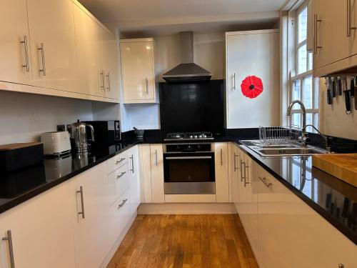 eine Küche mit weißen Schränken und schwarzen Arbeitsplatten in der Unterkunft Flora Cottage, in the heart of the city in Salisbury