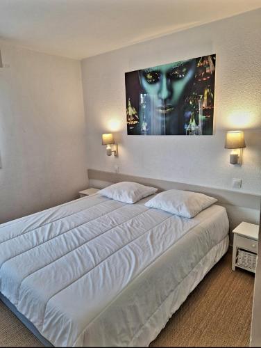 une chambre avec un grand lit blanc avec un tableau sur le mur dans l'établissement Superbe appartement climatisé, résidence avec piscine, proche des commerces et du port, au Cap d'Agde