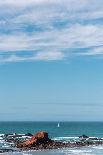 a view of the ocean with a sail boat in the distance at Seaview Ensuite rooms in Sagres centre - Casa Maluka in Sagres