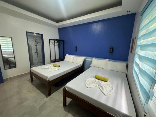 a room with two beds and a blue wall at GreenEscape Beach Resort in Puerto Galera