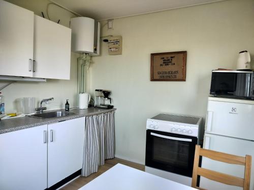 a kitchen with white cabinets and a sink and a stove at Hytte med udsigt til Stege Nor in Stege