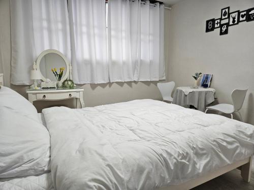 a white bedroom with a white bed and a mirror at Tov Stay Atti in Pyeongtaek