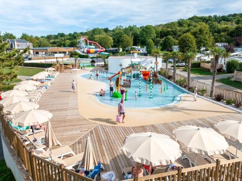 une piscine extérieure dans un parc avec des personnes et des parasols dans l'établissement Confort Mobilhome climatisé dans un camping 5 étoiles, à Houlgate