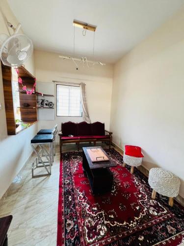 a living room with a couch and a red rug at CozyNest Retreat in Belgaum