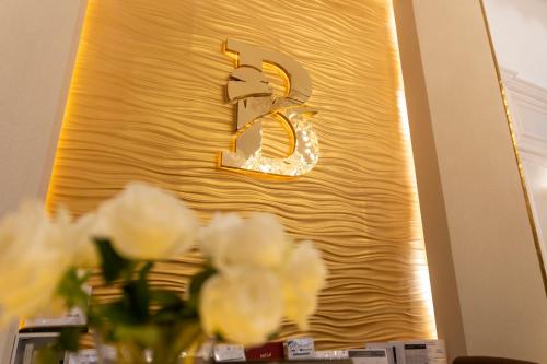 a gold wall with a sign with white flowers at Bellevue Park Hotel in Taif