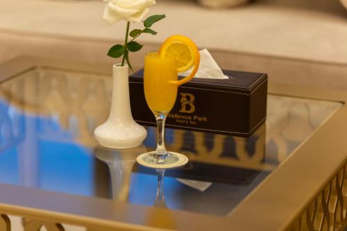 a glass of orange juice and a vase with a flower at Bellevue Park Hotel in Taif