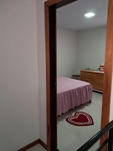 a bedroom with a bed with a pink bedspread and a mirror at Casa em Vivendas - Pedra Azul in Domingos Martins