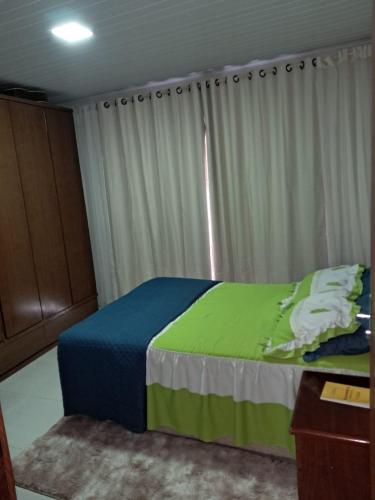 a bedroom with a bed with a green and blue blanket at Casa em Vivendas - Pedra Azul in Domingos Martins