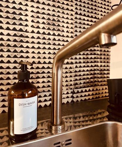 une bouteille de liquide vaisselle humide assise à côté d'un évier dans l'établissement Centre Historique Coup de Coeur - 5 mins Aéroport, à Blagnac