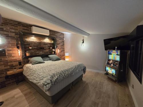 - une chambre avec un lit, une télévision et un mur en briques dans l'établissement Charming cozy villa, à Saint-Victoret