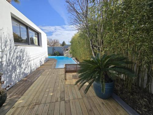 une terrasse en bois avec une plante en pot à côté d'une piscine dans l'établissement Charming cozy villa, à Saint-Victoret